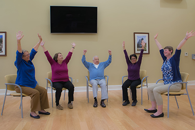 a group of adults of all ages performing seated exercises