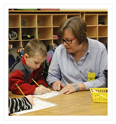 older woman tutoring a young boy in a classroom
